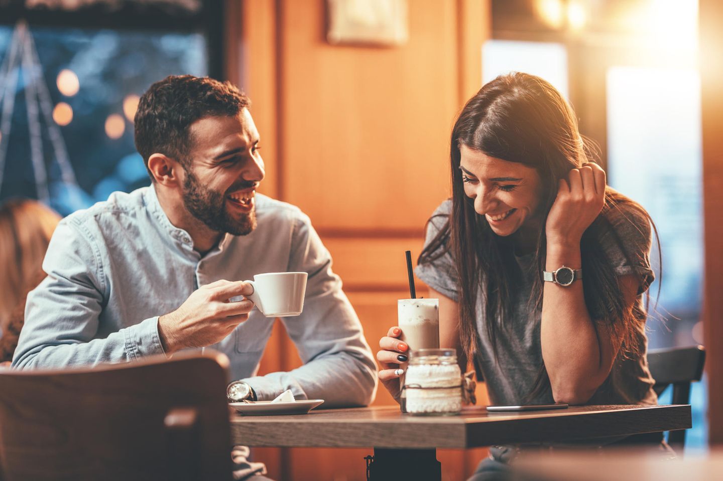 Der Funke: ein junges Paar setzt lachend an einem Tisch in einem Café