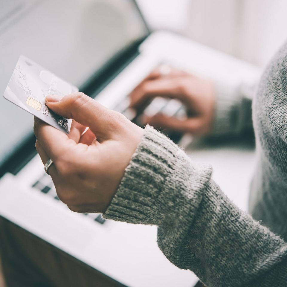 Finanzfallen: eine Frau sitzt am Laptop und hält eine Kreditkarte in der Hand
