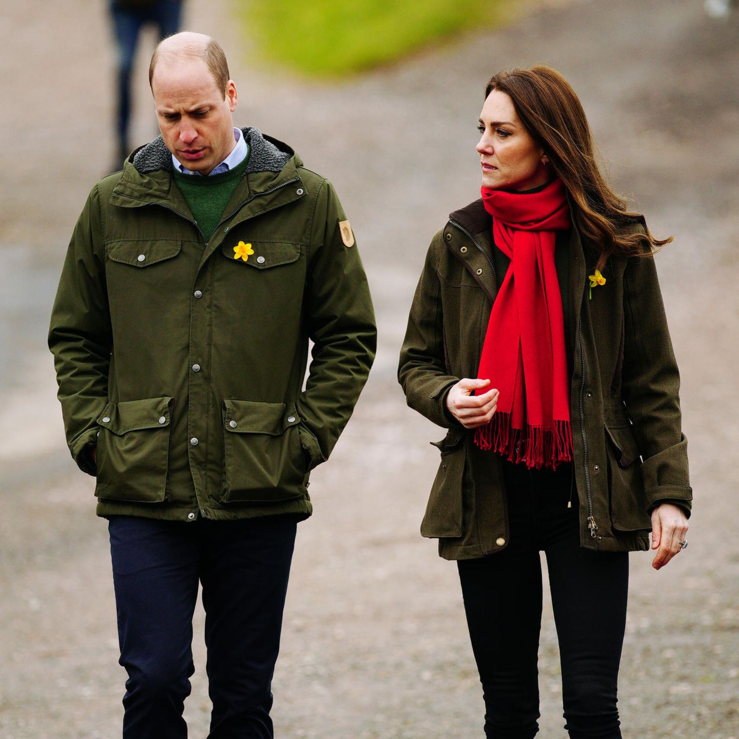 Im beinahe komplett identischen Outfit erscheinen Prinz William und Herzogin Catherine zu einem Termin im Rahmen ihres Wales-Besuchs. Sowohl Kate als auch ihr Mann setzen auf ihre dunkelgrüne Barbour-Jacke mit walisischem Nationalblumen-Anstecker sowie einer dunklen Jeans. Boots in Cognac komplettieren den Outdoor-Look. 