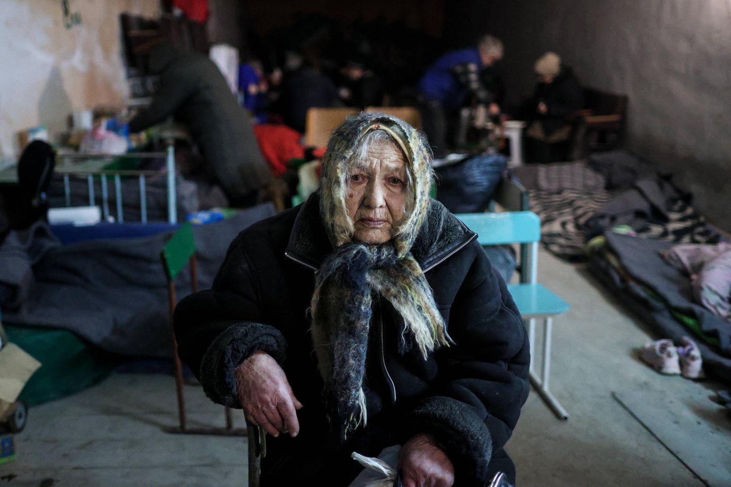 Eine alte Frau sitzt in einem Keller, um sich vor den Bombenanschlägen zu schützen.