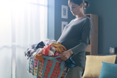 Alexandra Zykunov: eine schwangere Frau trägt einen vollen Wäschekorb