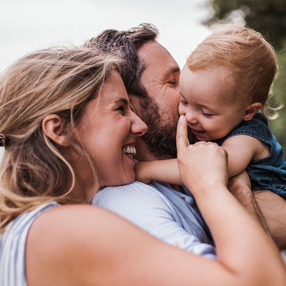 Überraschende Studie: junge Eltern mit ihrem Baby auf dem Arm