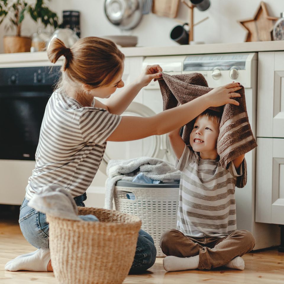 Eine Mutter macht zusammen mit ihrem Sohn die Wäsche.