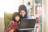 Team Rabeneltern: Mutter schaut mit Kind auf Laptop