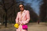 Eine Chanel-Tasche ist schon ein Zeichen von Luxus, doch warum eine ausführen, wenn man auch zwei tragen kann. In poppigen Gelb und Pink macht die Doppelbeladung mit Mini-Flapbags auf jeden Fall etwas her und rundet Olga Ferraras Outfit aus Boucle-Playsuit und Perlenstiefeletten stilvoll ab.
