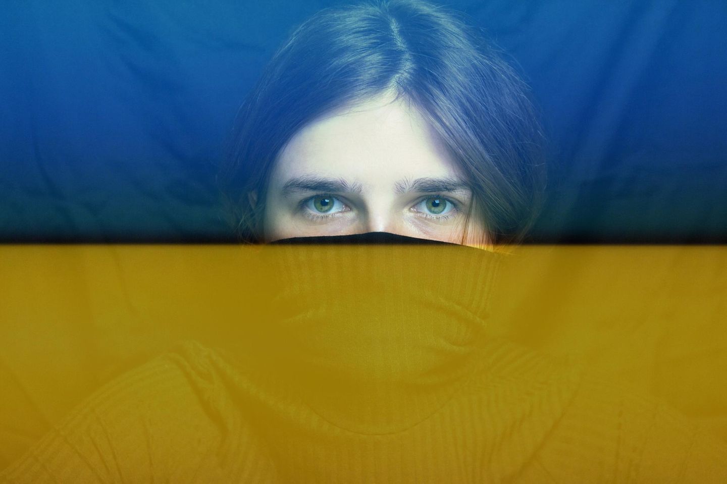 Ukraine-Krieg: Augen einer Frau blicken durch die gelb-blaue Flagge der Ukraine