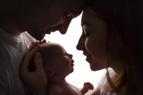 Mutter und Vater halten Neugeborenes im Arm
