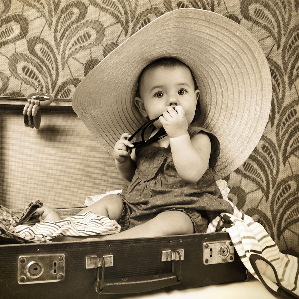 Schwarz-weiß Fotografie eines Babys, das in einem Koffer sitzt.