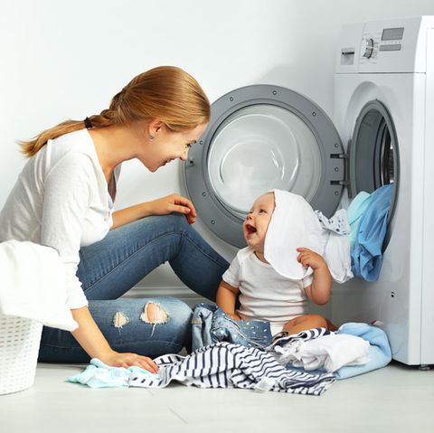 Mutter und Kind nehmen Wäsche aus der Waschmaschine