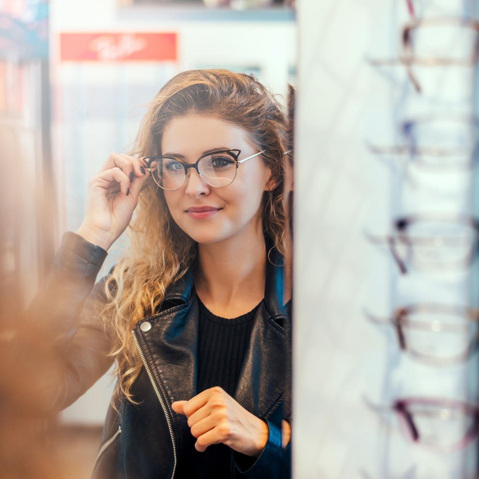 Björn Krause:eine Frau probiert vor dem Spiegel eine neue Brille auf