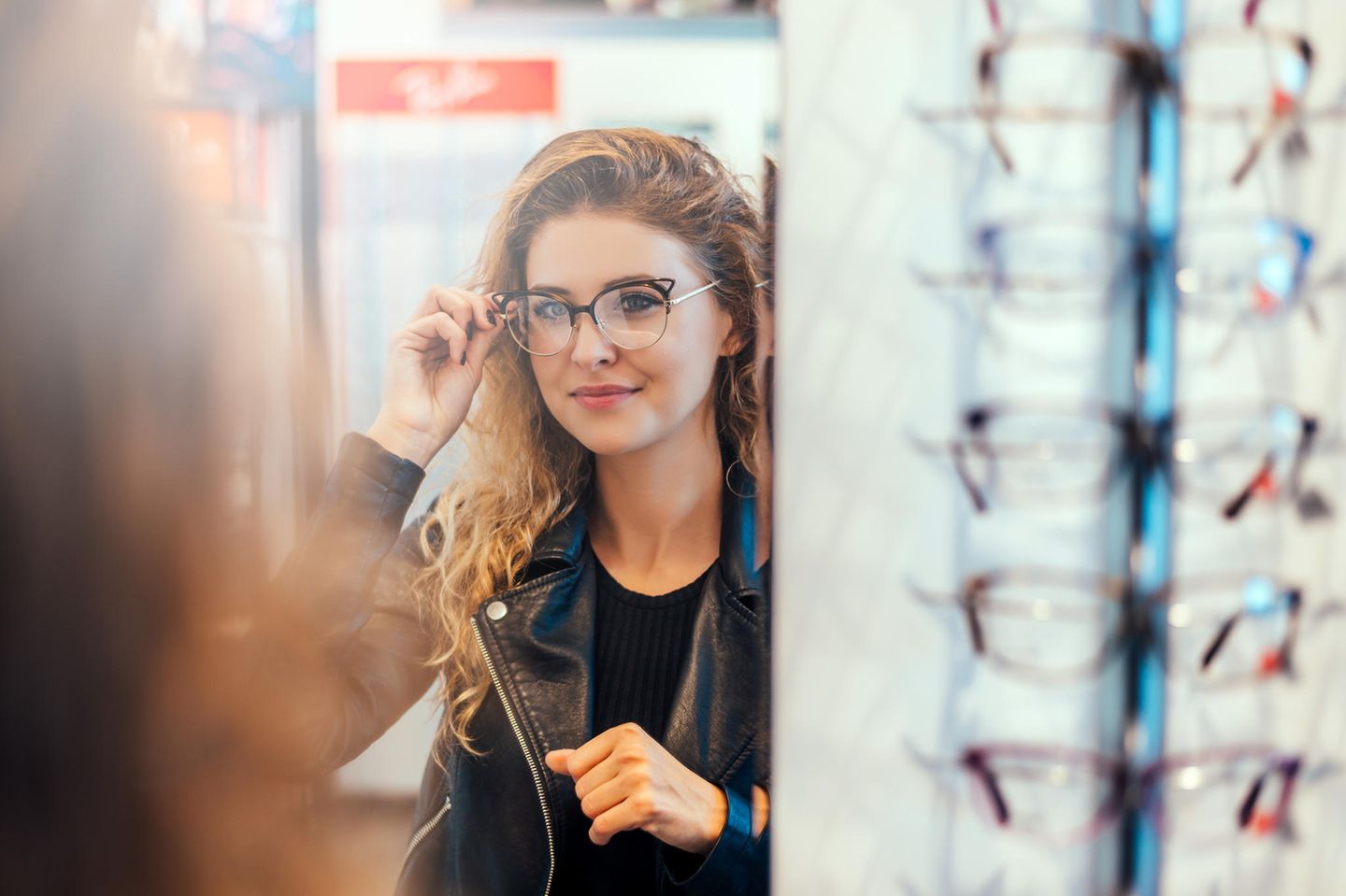 Björn Krause:eine Frau probiert vor dem Spiegel eine neue Brille auf