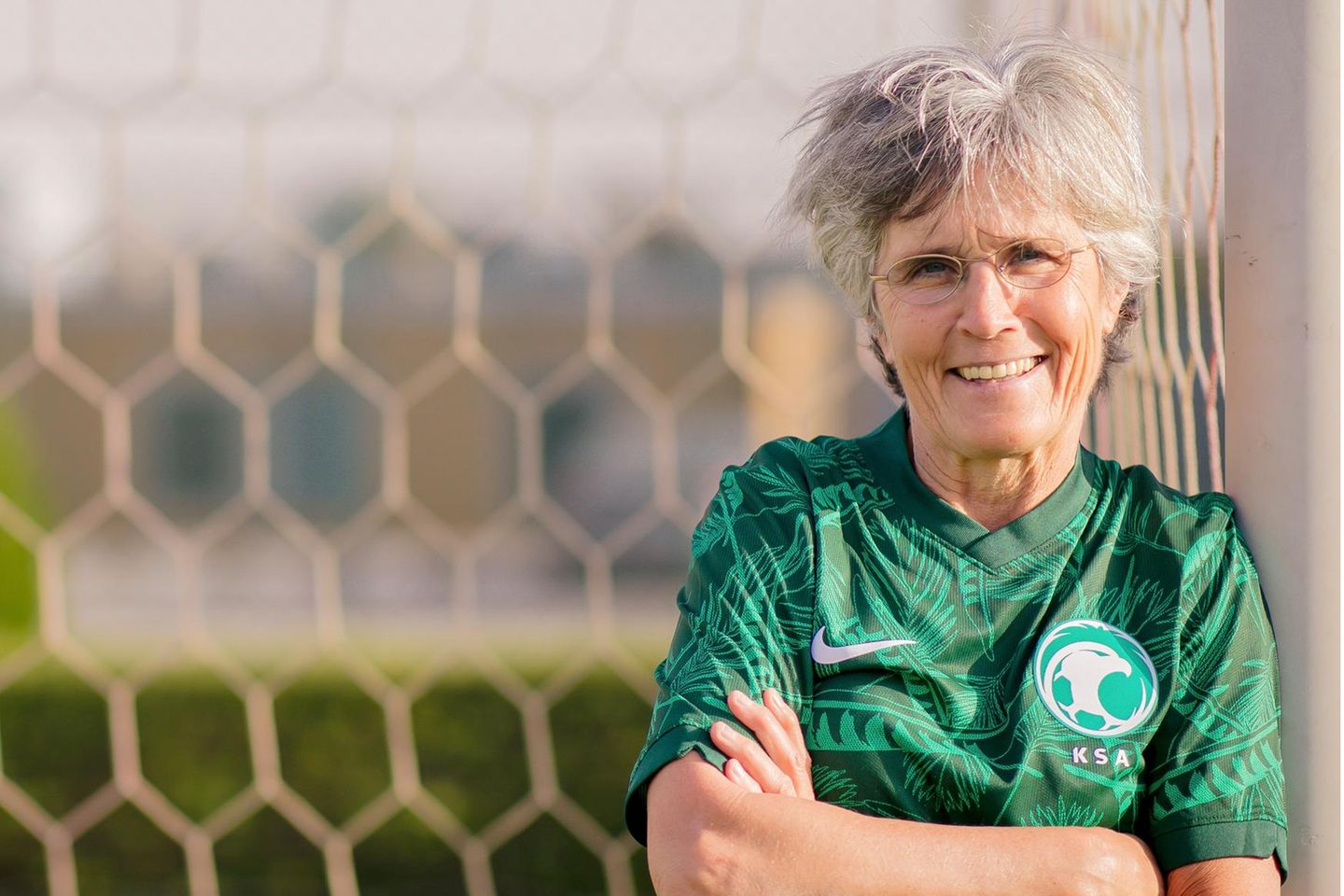 Monika Staab: eine ältere Frau im grünen Trikot lehnt gegen ein Fußballtor