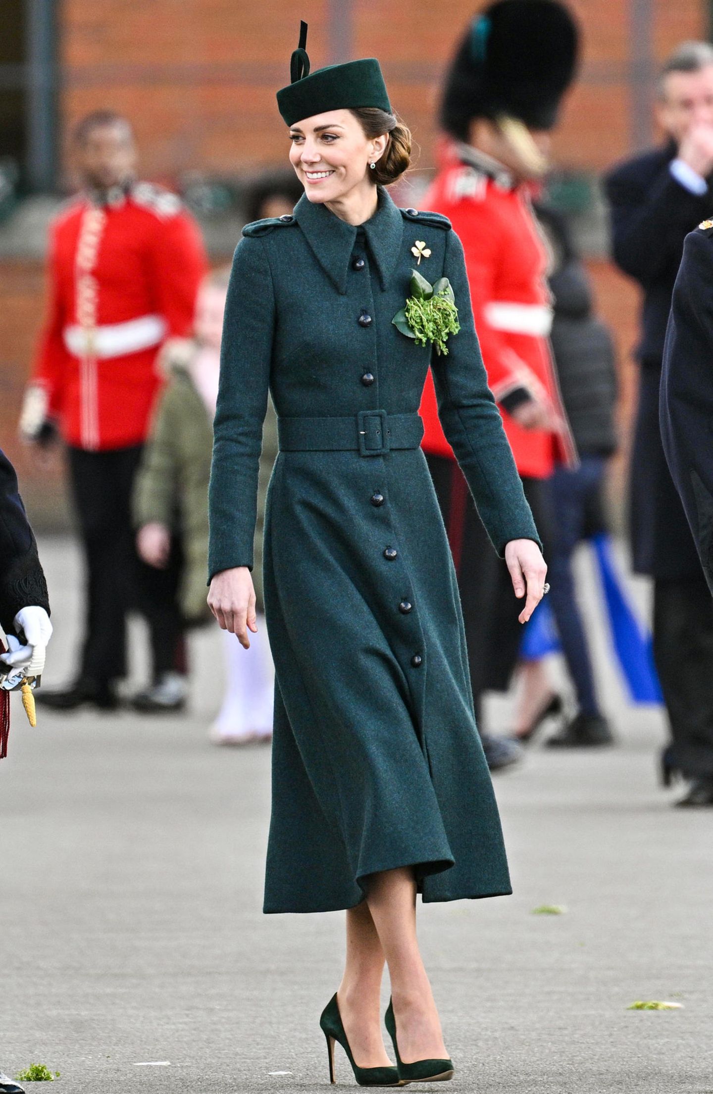 Bei der diesjährigen "St. Patricks Day"-Parade zeigt sich Herzogin Catherine in einem grün-melierten Mantelkleid mit Taillengürtel. Zu dem dunklen Grünton greift sie fast in jedem Jahr – die Art des Kleides unterscheidet sich allerdings immer. Dazu trägt sie einen grünen Hut und einen tiefen Dutt. 