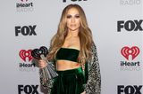 Jennifer Lopez wechselt bei den iHeartRadio Music Award insgesamt zwischen drei Outfits. Für den Red-Carpet Look entscheidet sich die 52-Jährige für ein smaragdgrünes Bandeau aus Samt mit der passenden Hose. On Top trägt die Sängerin eine lange Seidenrobe im Leo-Print.