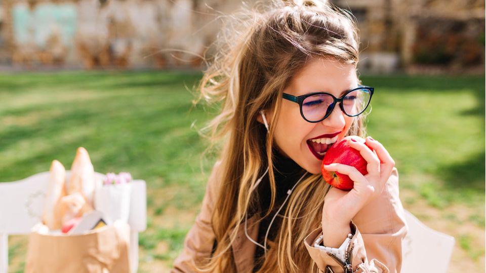 Frau im Park genießt einen Apfel beim Picknick