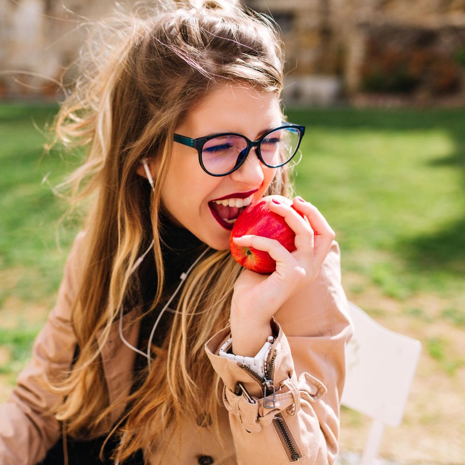 Frau im Park genießt einen Apfel beim Picknick