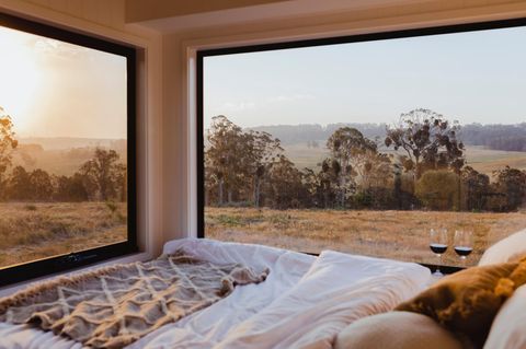 Tiny Houses: Blick von einem Bett in einem Tiny Haus auf Felder und Hügel