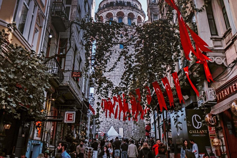 Istanbul: eine Fußgängerzone mit vielen Menschen, Bäumen und gespannten türkischen Flaggen