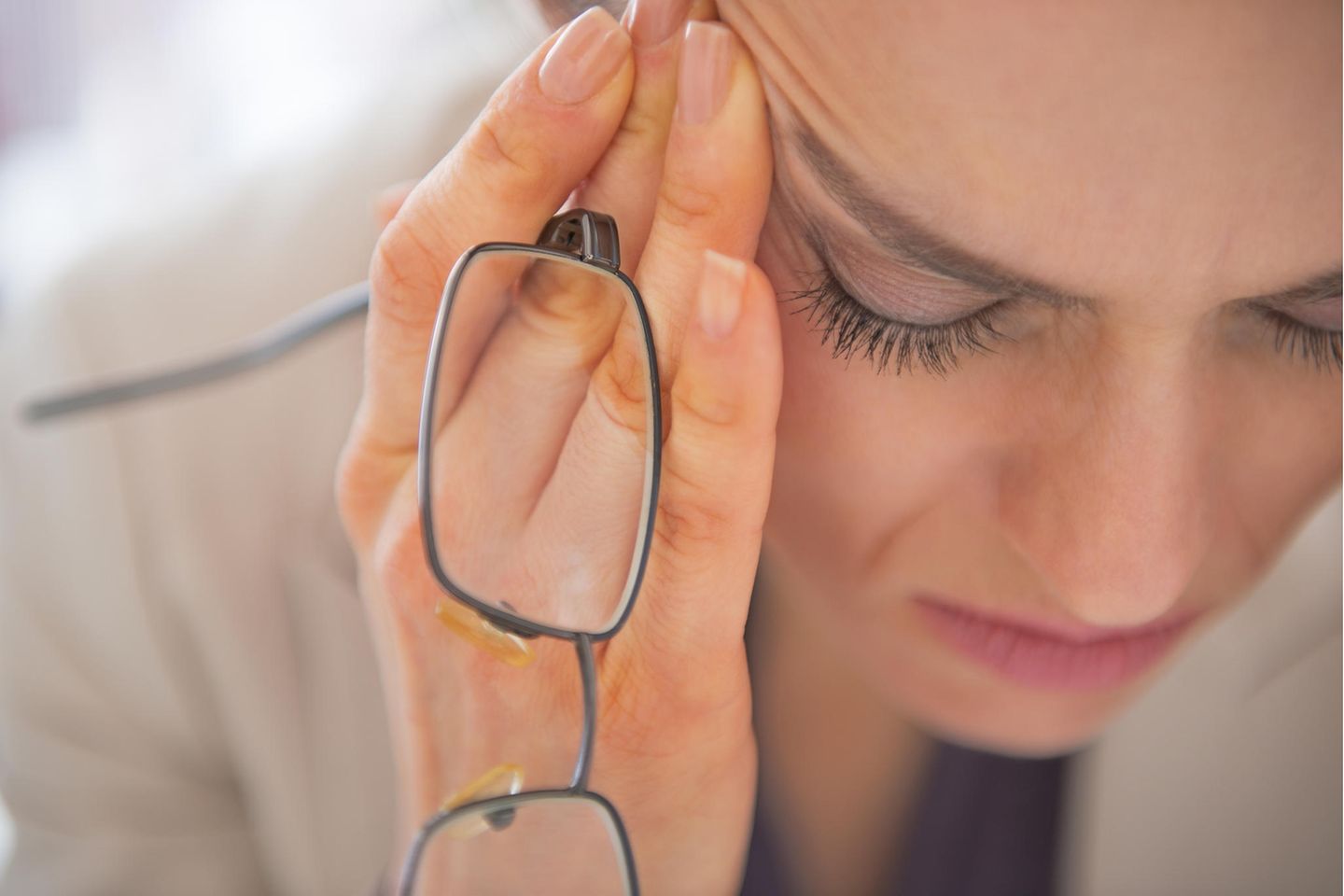 Burn on: Nahaufnahme einer gestressten Frau mit Brille, die den Kopf in den Händen hält