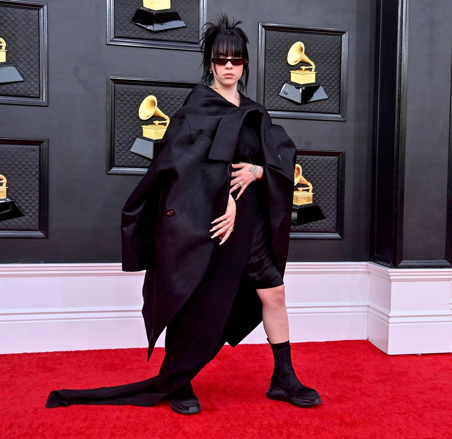 Billie Eilish zeigt auch bei den Grammys wieder ihren ungewöhnlichen Style. Der XXXL-Blazer zum knielangen Seidendress und Boots wir etwas anders getragen als üblich.