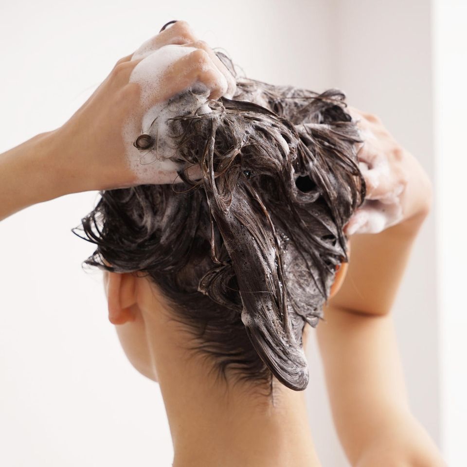 brünette-frau-wäscht-haare-mit-shampoo-gegen-fettige-haare