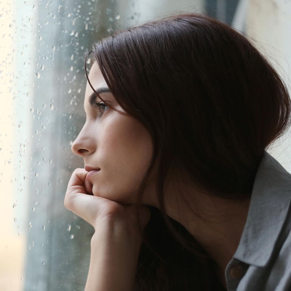 Studie erforscht "Melancovid": Frau schaut nachdenklich aus dem Fenster