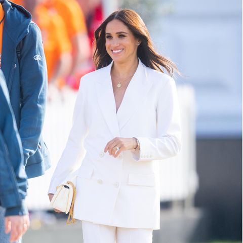 Bei ihrer Ankunft in Den Haag zeigt sich Meghan in einem weißen Power-Suit von Valentino. Die Frau von Prinz Harry strahlt darin förmlich mit der Sonne um die Wette. Die kleine Tasche, ebenfalls von Valentino, verleiht ihrem Business Look das gewisse Etwas.