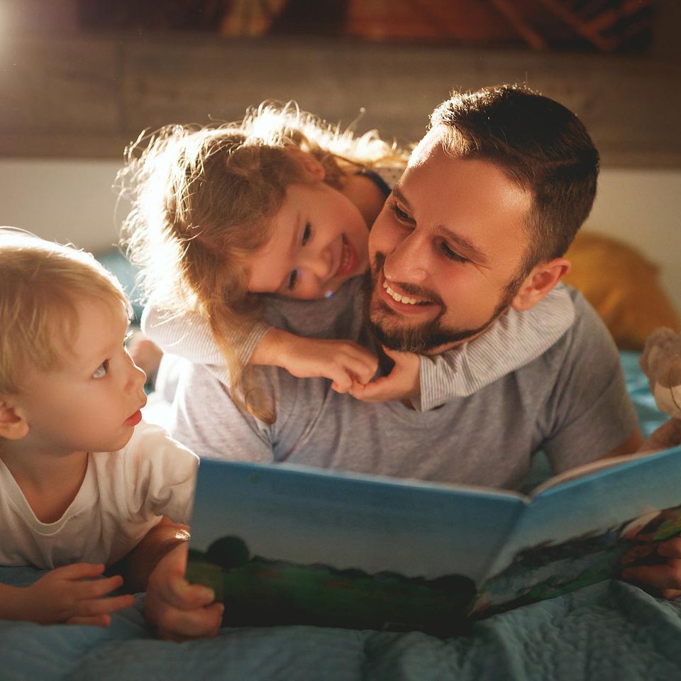 Mann liest Kindern Gute-Nacht-Geschichte vor