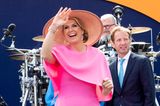 Das pinkfarbene Wow-Dress ist von Natan Couture, einem der Lieblingslabels der Königin. Es reicht knapp bis zum Knie, erhält durch einen großen Volant im Brustbereich einen besonderen Twist.