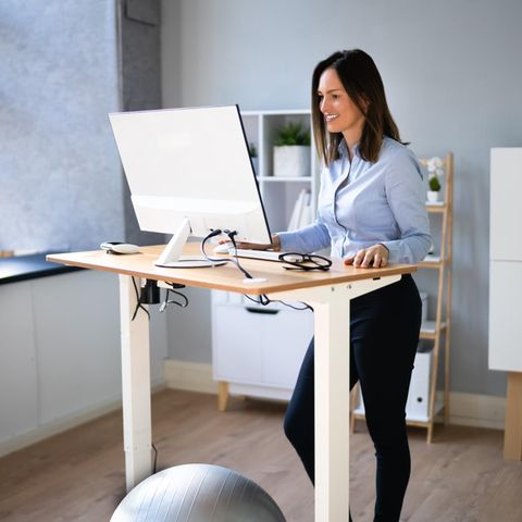 Frau arbeitet an einem Stehtisch, höhenverstellbarer Schreibtisch