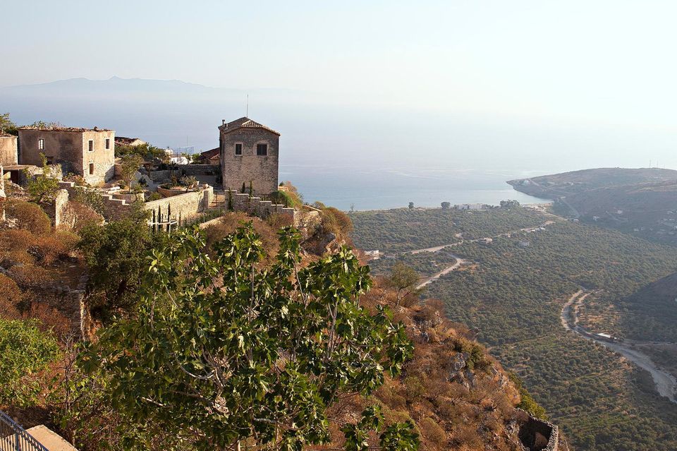 Albanien: ein Berg mit Gebäuden auf der Spitze. Im Hintergrund ist das Meer