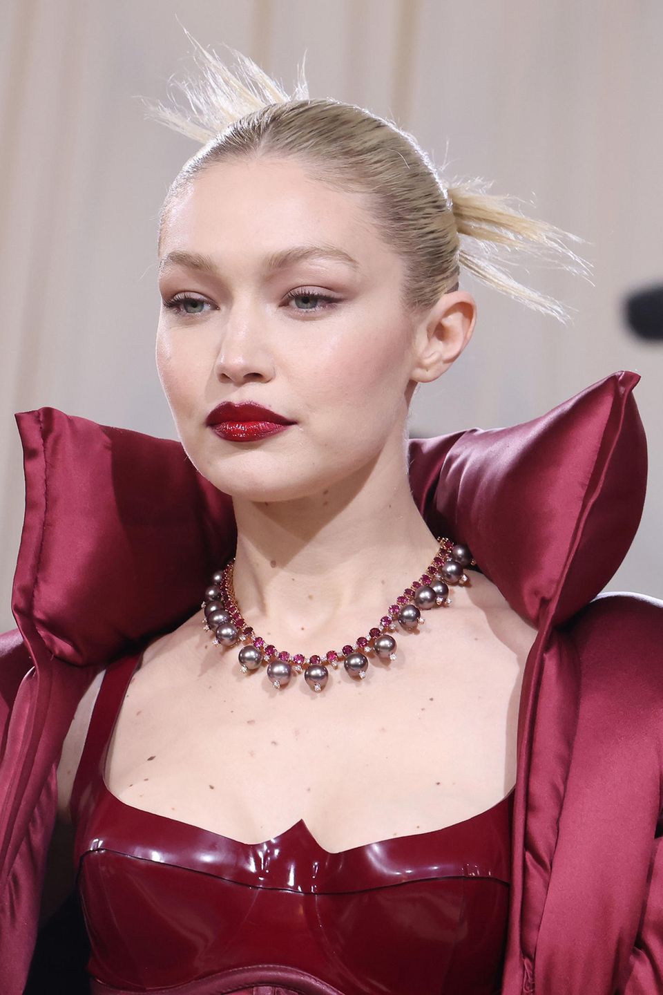 Mit Fokus auf ihre Lippen ergänzt Topmodel Gigi Hadid perfekt ihren dunkelroten Power-Suit. Eine strenge Frisur und eine große Statement-Kette machen den Beauty-Look der 27-Jährigen perfekt.