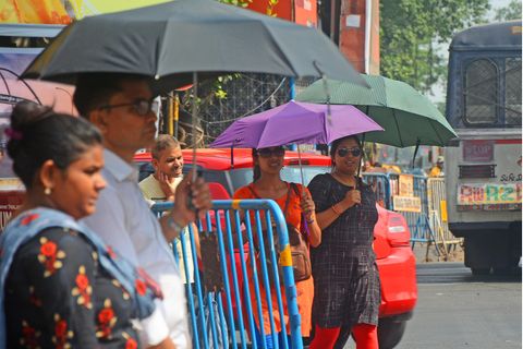 Menschen in Indien schützen sich mit Regenschirmen vor der Sonne.