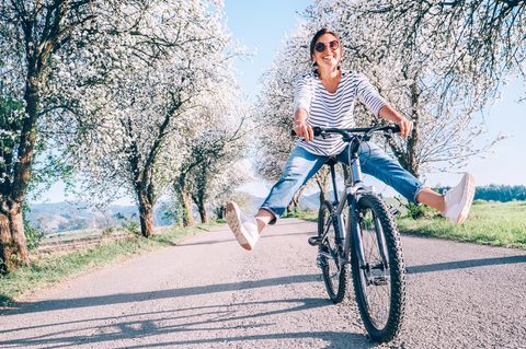Karina Lübke: Fröhliche Frau fährt bei gutem Wetter Fahrrad