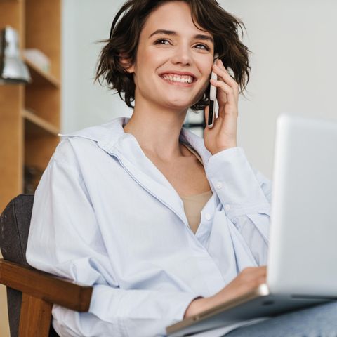 Berufswechsel: Frau sitzt mit Handy am Ohr am Laptop