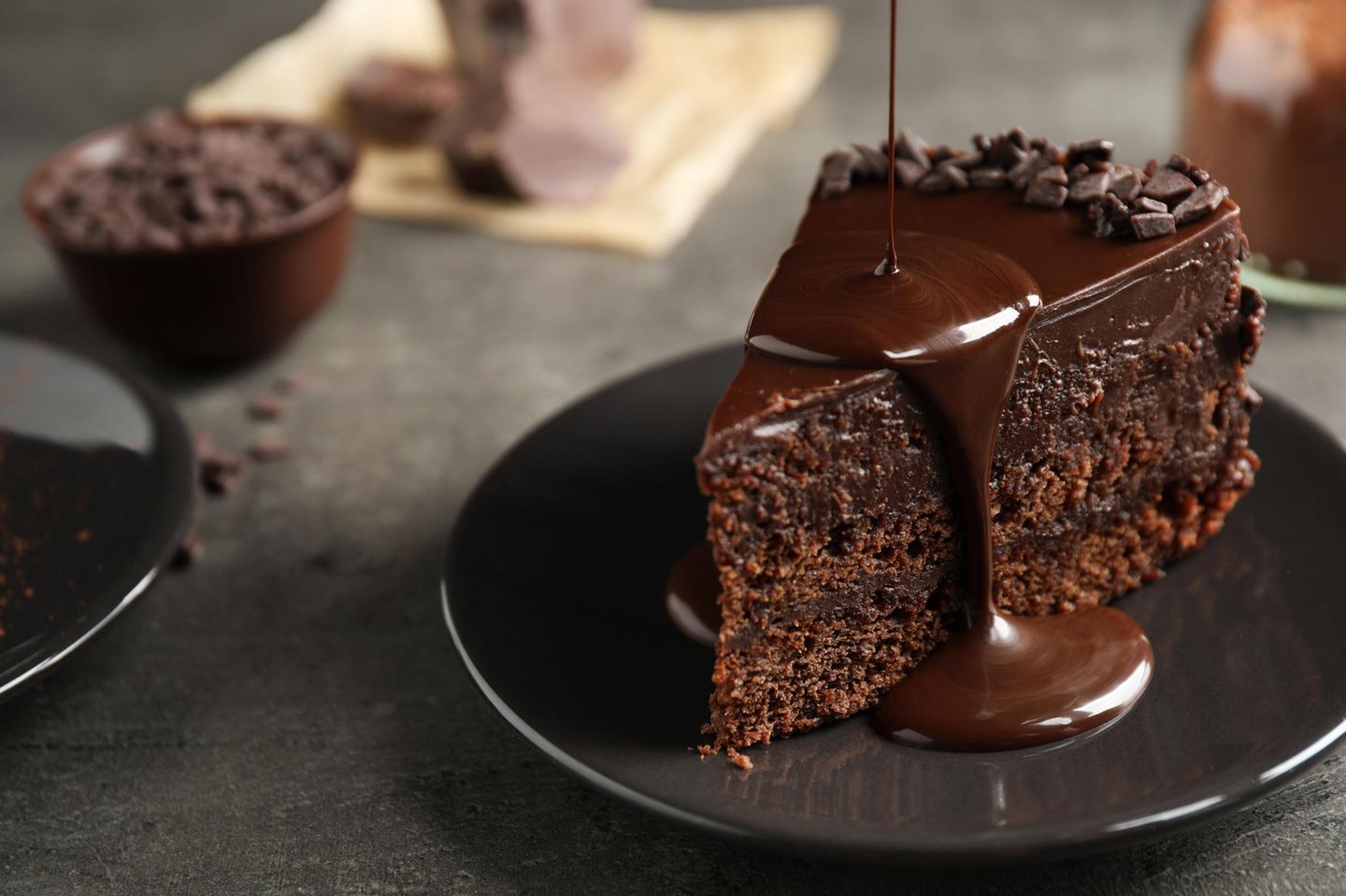 Ein Stück dunkler Schokoladen-Kuchen, das mit einer Glasur verziert wird