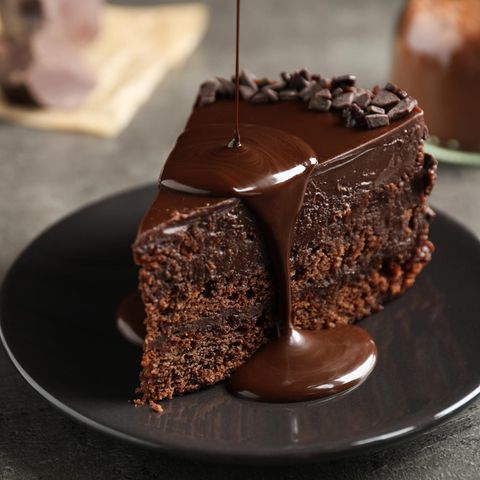 Ein Stück dunkler Schokoladen-Kuchen, das mit einer Glasur verziert wird
