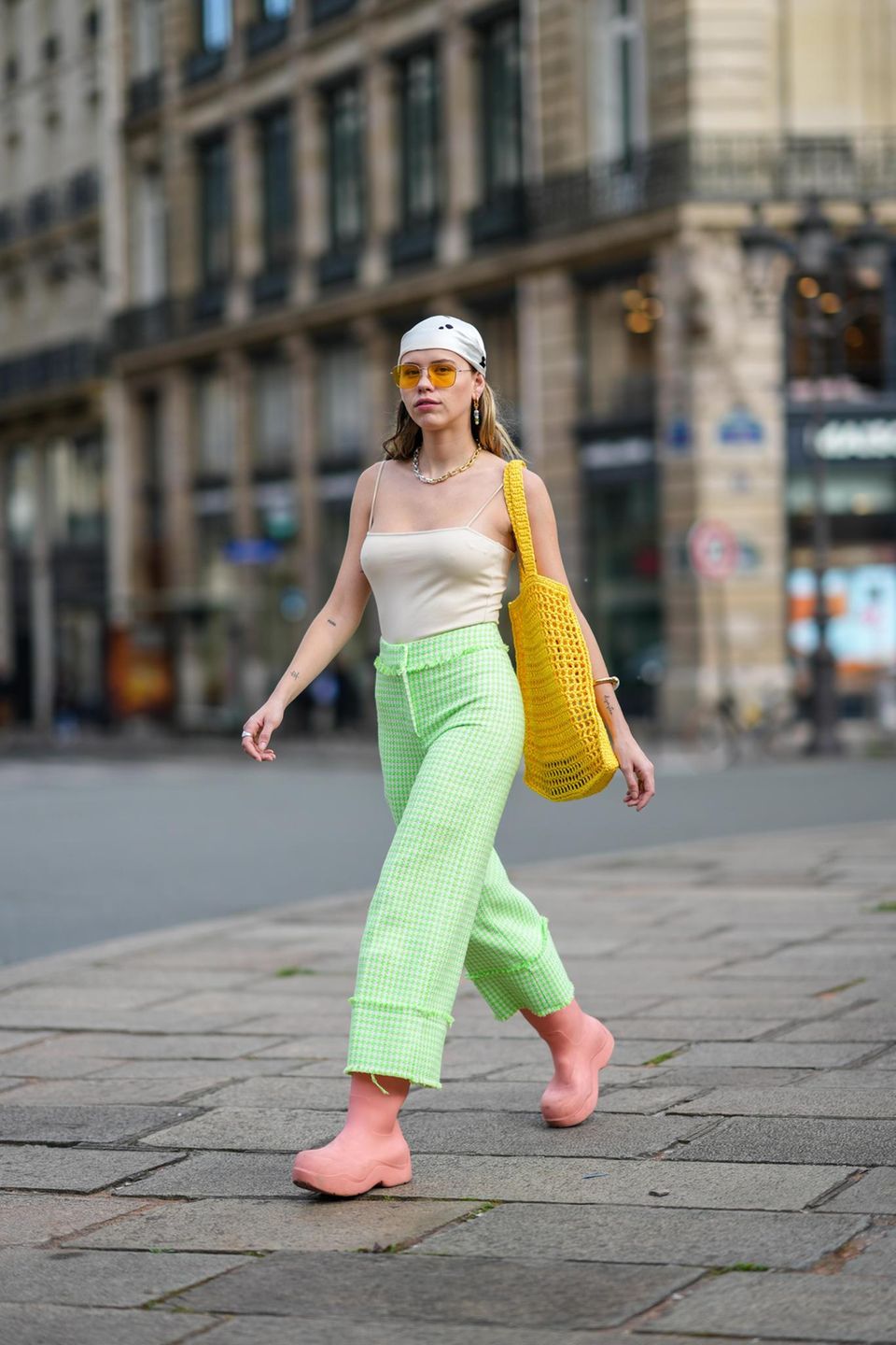 Frau mit grün-karierter weiter Hose und großer Sonnenbrille