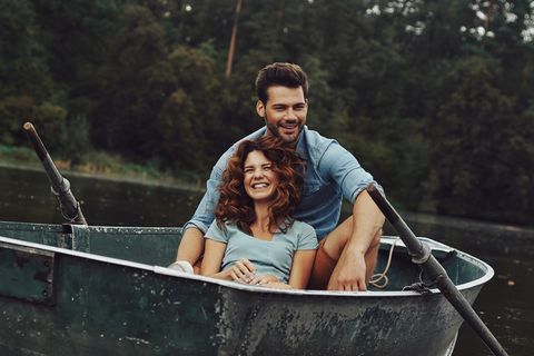 Beziehungsformen: Mann und Frau kuscheln in einem Ruderboot auf einem See und lachen