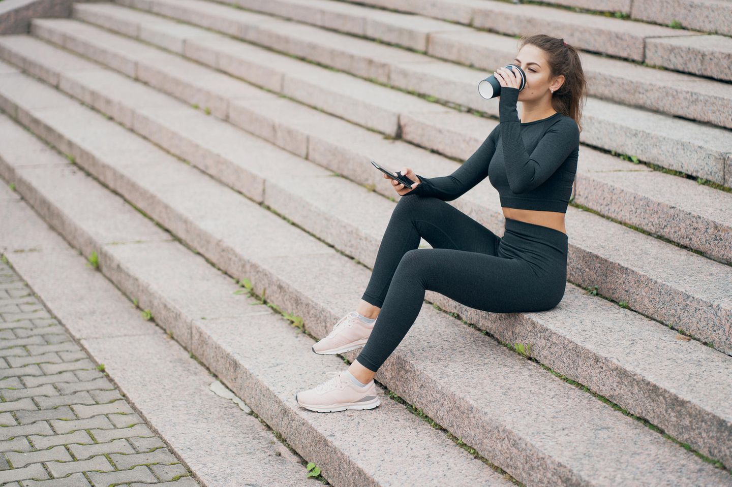 Frau trinkt Kaffee nach dem Sport: Die 4 besten Lebensmittel gegen Muskelkater