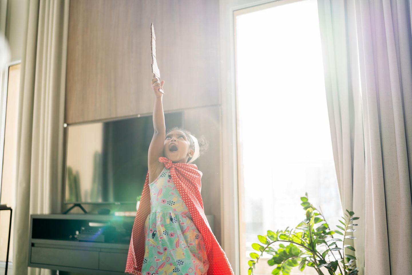 Mädchen spielt mit Schwert und Krone im Wohnzimmer