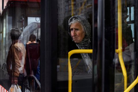 Eine ältere Frau sitz in einem Bus und flüchtet vor dem Krieg in der Ukraine