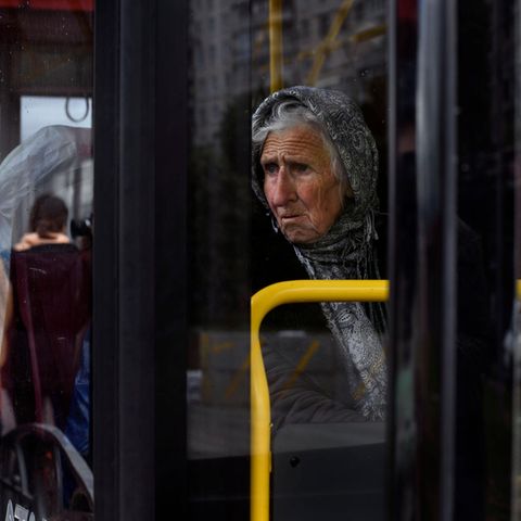 Eine ältere Frau sitz in einem Bus und flüchtet vor dem Krieg in der Ukraine