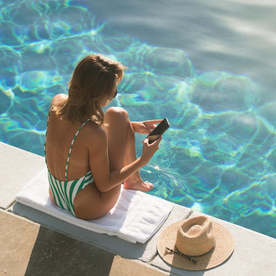 Frau am Pool mit Smartphone
