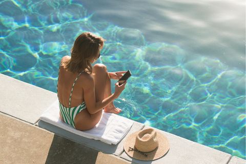Frau am Pool mit Smartphone