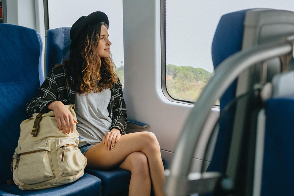Eine Frau sitzt in einem Zug und schaut aus dem Fenster