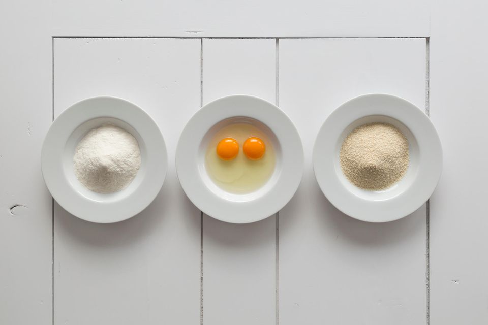 3 weiße Teller mit Mehl, Eiern und Paniermehl drin
