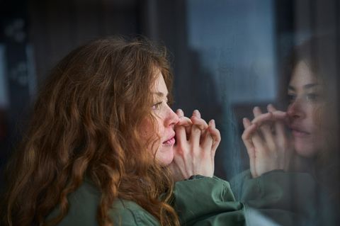 Junge Frau schaut traurig aus dem Fenster
