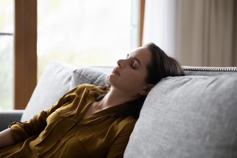 Chronisches Fatigue-Syndrom: eine Frau liegt erschöpft auf dem Sofa