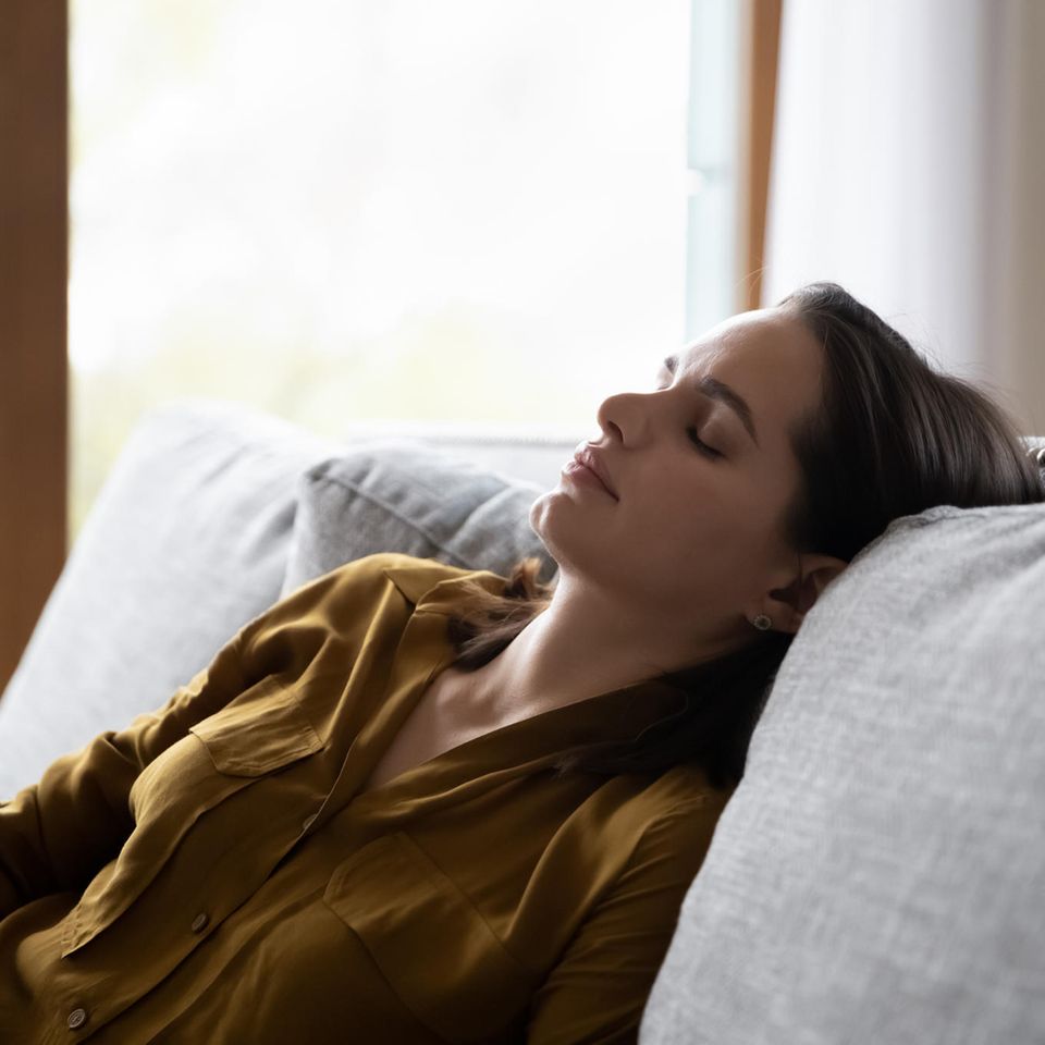 Chronisches Fatigue-Syndrom: eine Frau liegt erschöpft auf dem Sofa